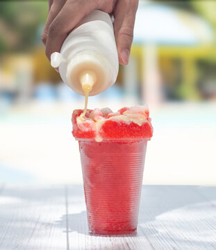 Cepillado, Raspado o hielo Granizado de Cola roja con mano colocando leche Condensa