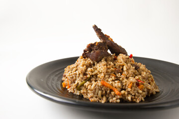 nasi kebuli, indonesian food with brown rice spicy and goat meat on black plate close up white background
