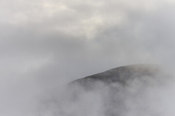 Caherconree peeking out of the early morning clouds, Ireland