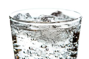 Close-up of a glass filled with sparkling water, ice cubes floating, and bubbles rising to the surface. Refreshing and invigorating beverage.