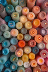 An abundant collection of small candles in various colors and shapes, tightly arranged to fill the entire frame. The candles display a range of hues from pastel to bright.
