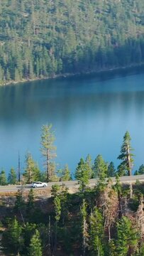 Vertical Screen: Aerial video of a beautiful mountainous landscape with Lake Tahoe surrounded by lush forests in California. The serene lake and trees create a picturesque scene.