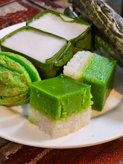 Kuih Seri Muka and Kuih Cara are on a white plate. These are delicious and popular Malaysian traditional snacks. Close-up food photo.