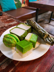 Kuih Seri Muka and Kuih Cara are on a white plate. These are delicious and popular Malaysian traditional snacks. Close-up food photo.