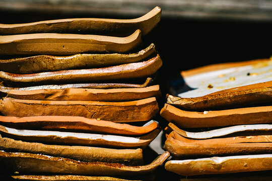 Stacks of rustic earthenware plates on wooden tables in the sunlight