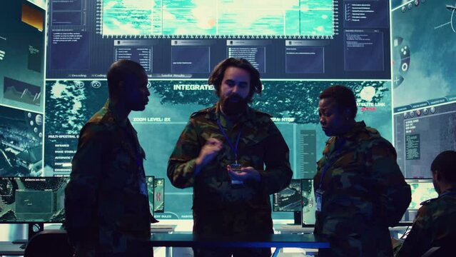 Army officers review data on a hologram to create a brief for the new mission, thinking of an operational plans after gathering important field information. High tech holographic image. Camera B.