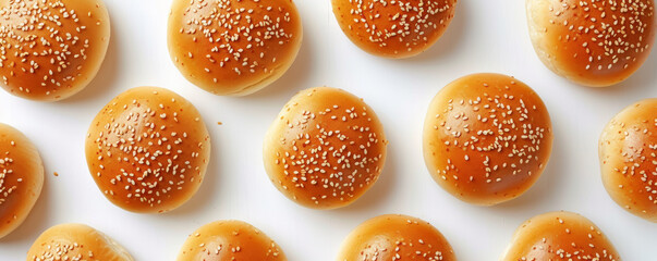 Fresh sesame seed burger buns arranged on white background, top view. Food and bakery concept