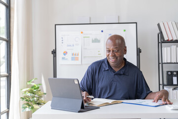 Creative african businessman senior american worker using computer device in office,chat online, thinking business solution planning difficult decision pondering strategy come up with idea.