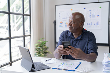 Portrait of happy African American small business owner. Millennial black smiling, sitting and using the laptop, and holding a cup of coffee work in modern office.