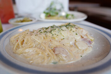 Spaghetti carbonara with ham and cheese in white plate on table