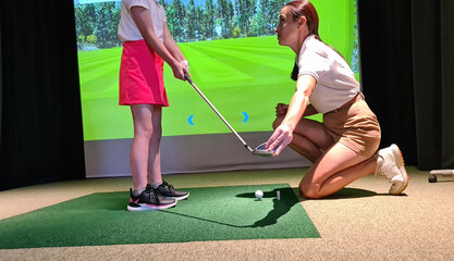 Young Golfer Receiving Instruction From Coach In Indoor Golf Simulator