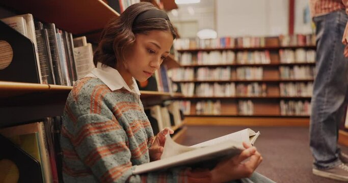 Student, woman and book on floor in library for reading, literature research or studying for knowledge. Gen z girl, novel or search for academic information for scholarship with education or learning