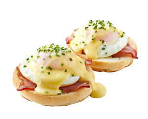 Delicious eggs benedict with ham, topped with hollandaise sauce and chopped chives, served on English muffins, perfect for breakfast or brunch.