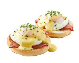 Delicious eggs benedict with ham, topped with hollandaise sauce and chopped chives, served on English muffins, perfect for breakfast or brunch.