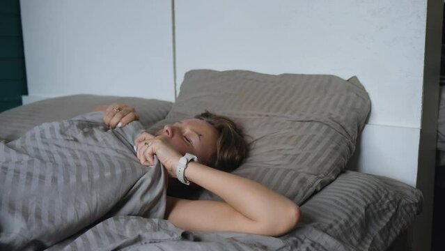 It's pesky insect season: a pretty young blonde woman is forced to hide from a pesky fly under the covers, trying to escape its annoying attempts to disturb her sleep.