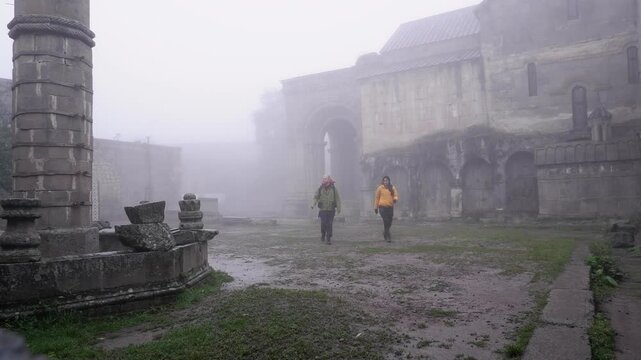 Young pair enjoy solitude on wet foggy day in Tatev Monastery, Armenia