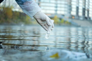 Close up of scientist with white glove holding a test tube with water in his hand. Water pollution...