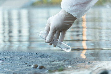 Close up of scientist with white glove holding a test tube with water in his hand. Water pollution...