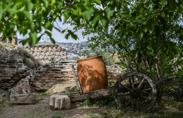 Ethnographic wooden cart with pot hidden in the shadows of a tree