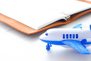 離陸を待つ旅客機と、開いたノートで、旅行を計画しているイメージ
