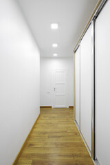 White interior door with sliding wardrobe in the hallway