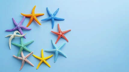 Obraz premium : A playful composition of colorful painted starfish arranged as a summer sunburst on a pastel blue background. Vibrant summer creative concept, flat lay, top view, with plenty of copy space.