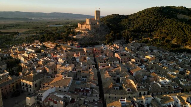 Historic and medieval Biar city perspective from above. Drone going backwards above the od town centre. Castel in top of the hill. Bhurch in the old center of the city. Travel destination in Alicante.