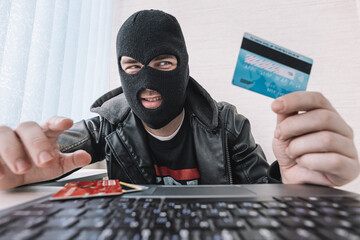 male thief holds a credit card in his hand and picks up a password to steal money. theft from...
