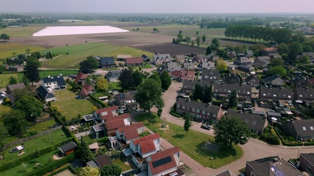 Aerial drone footage of Budel residential area in Brabant, showcasing houses, rooftops, and surrounding meadows. Captures the serene countryside town landscape. Location: Budel, Netherlands