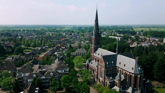 Drone captures the picturesque view of Budel, featuring Onze Lieve Vrouw Church, quaint streets, and rooftops. Location: Budel, Netherlands (Budel, Nederland).