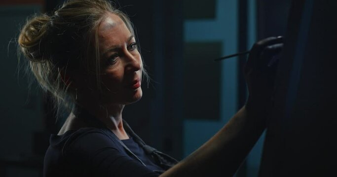 Woman Painting Leopard Portrait in Dark Studio