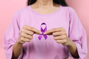 Woman Hand Showing Purple Ribbon Isolated On Pink Background. Domestic Violence Awareness
