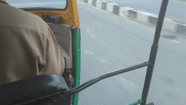 POV of a tourist person travelling in an auto rikshaw taxi while the driver cruises along the highway road in india 