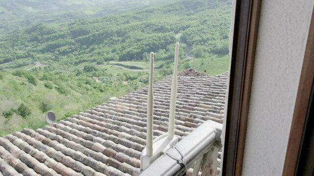 A WiFi signal extender mounted on the outside of a window, surrounded by a tranquil countryside. Slow motion panning.