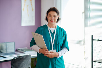 Portrait of cheerful medical nurse holding clipboard