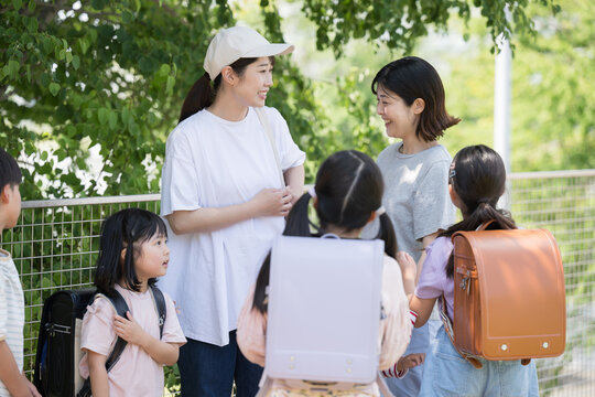 小学生と保護者、朝の通学の登校班の送迎の様子　子供たちの顔無し 主婦の井戸端会議