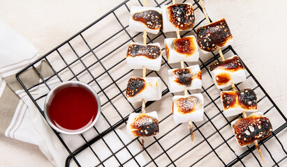 Marshmallow skewers and and strawberry, cherry, grame on light wooden background. Summer party food