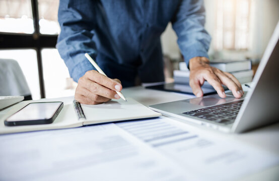 Close-up shot, asian businessman take a note and working with laptop at office. legal expert, professional lawyer checking business data and contract before giving advice to customers