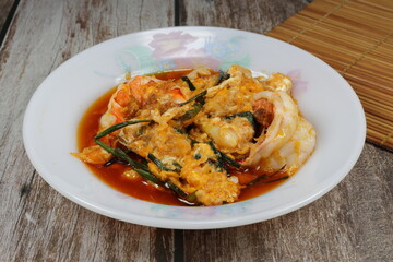 Fried fresh peeled tiger prawn dressing with red curry sauce serving on the plate. Famous seafood menu in Asian restaurant.