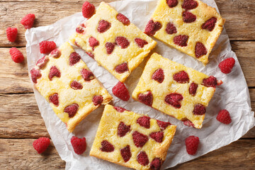 Delicious sweet dessert custard pie with fresh raspberries close-up on parchment on the table. Horizontal top view from above