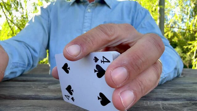 Close up of man hands playing csrds shuffle in freestyle. Outdoor people leisure activity at the park. Weekend active fun lifestyle with friends. Board games concept. Adult male play cards on table