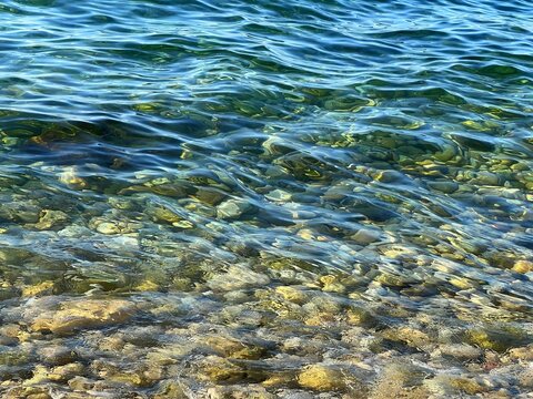 Blue sea water on pebbly beach