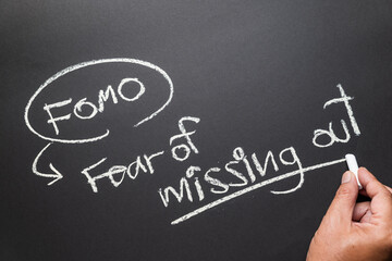 Hand writes the FOMO marketing, or Fear of Missing Out with chalk on the chalkboard