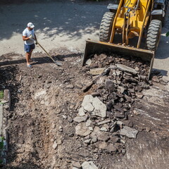 Naklejka premium Russia Samara June 29, 2023: Bulldozer works on the repair of the intra-block road and sidewalk.