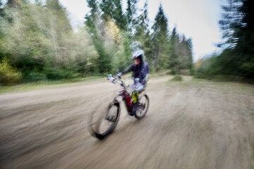 Obraz premium Motion blur. Cyclist man riding electric mountain bike outdoors. Male tourist biking along trail in the forest. Concept of sport, active leisure and nature.