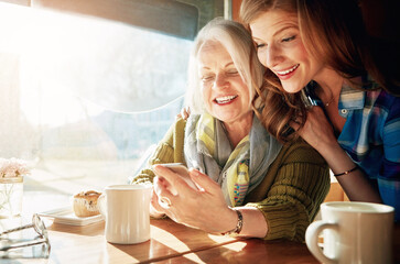 Mother, daughter and mobile phone in cafe with coffee for social media, internet meme or bonding together. Date, senior lady and woman for networking, communication or online post in restaurant