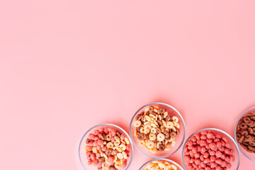 Breakfast cereals in glass plates on a pink background.