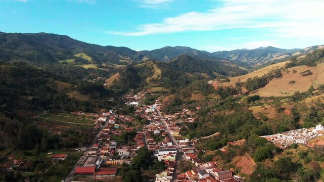Drone aerial landscape of housing downtown city suburbs street surrounded by forest mountain range in Delfim Moreira Minas Gerais Brazil South America