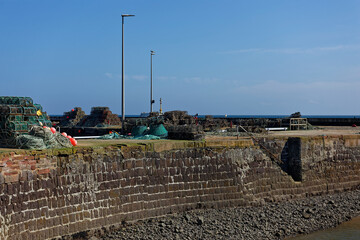 Hidden Stone steps to the Waters edge at low tide at Arbroath Harbour, with Fishing equipment and Pots scattered on the Quayside.