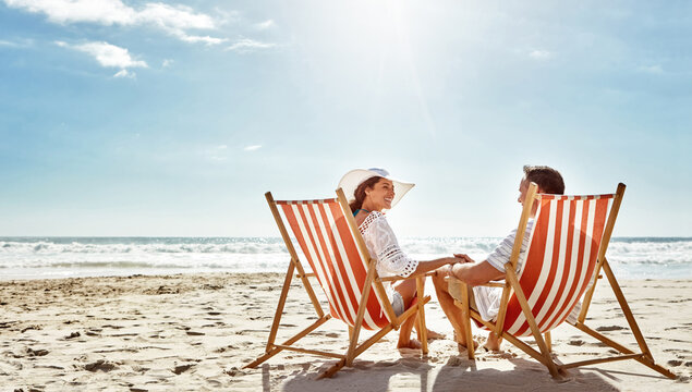 Couple, relax and beach chairs on sand for vacation, holiday or weekend break. Summer, man and woman together in nature with water for peace, travel or tourism in bali getaway with view